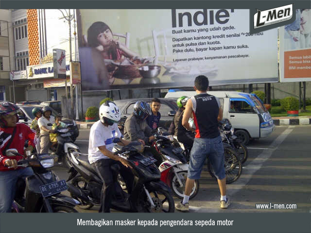 Membagikan masker kepada pengendara sepeda motor